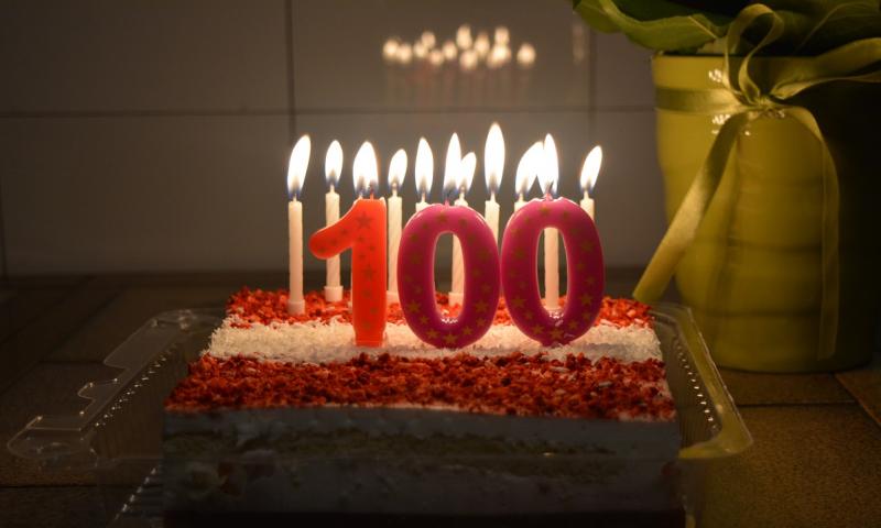 Birthday cake with candles and '100' candle.